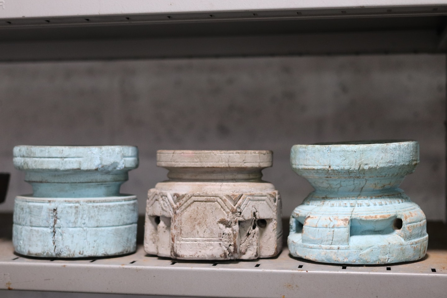 Three carved wooden objects on a shelf